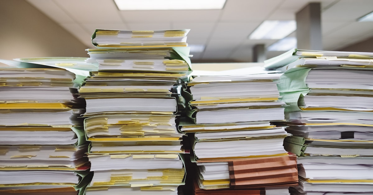 Pilhas volumosas de processos físicos com etiquetas em arquivo de cartório — o caos que a IA jurídica vai substituir
